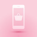 Paper cut Mobile phone and shopping basket icon isolated on pink background. Online buying symbol. Supermarket basket Royalty Free Stock Photo