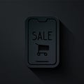 Paper cut Mobile phone and shopping cart icon isolated on black background. Online buying symbol. Supermarket basket Royalty Free Stock Photo