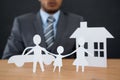 Paper cut out family chain with car and house at desk Royalty Free Stock Photo