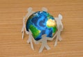 Paper cut of people standing in a circle around globe Royalty Free Stock Photo