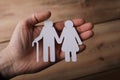 Paper cut of sn old couple in the hands of a man with a wooden background