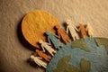 Paper cutout figures holding hands on Earth, symbolizing global unity and community under a sun Royalty Free Stock Photo