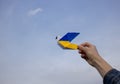 Paper dove of peace in his hand, wings are painted in yellow and blue colors of the Ukrainian flag against sky Royalty Free Stock Photo