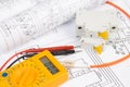 Paper electrical engineering drawings with circuit breaker and multimeter Royalty Free Stock Photo