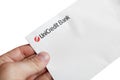 Paper envelope with Unicredit bank sign on it in male`s hand isolated on white background Royalty Free Stock Photo