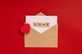 Paper envelope with a white sheet for text on a red background with hearts and the word `love` in wooden letters. Greeting card co Royalty Free Stock Photo