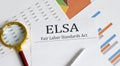 Paper with Fair Labor Standarts Act FLSA on a table with pen, charts and magnifier