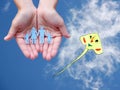Paper family in hands on blue sky background with colorful kite Royalty Free Stock Photo