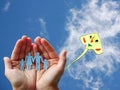 Paper family in hands on blue sky background with colorful kite Royalty Free Stock Photo