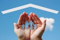 Paper family in hands with home on blue sky background Royalty Free Stock Photo