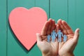 Paper family in hands on wooden background with red heart Royalty Free Stock Photo