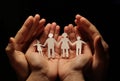 A paper family holding hands, with the protection of a woman`s hands, in turn in the hands of man. Royalty Free Stock Photo
