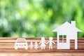 Paper family, house and car on wooden table with garden bokeh outdoor theme background Royalty Free Stock Photo