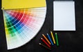 Paper fan paint swatch interior design, wall painting. Black background. White notebook, multicolored pencils, copy space Royalty Free Stock Photo