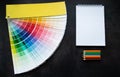 Paper fan paint swatch interior design, wall painting. Black background. White notebook, multicolored pencils, copy space Royalty Free Stock Photo