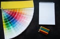 Paper fan paint swatch interior design, wall painting. Black background. White notebook, multicolored pencils, copy space Royalty Free Stock Photo