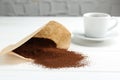 Paper filter, ground coffee and cup of drink on white wooden table, closeup Royalty Free Stock Photo