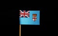 A paper Flag of Fiji on wooden stick on black background. Fiji is island state. Fiji belongs to Oceania