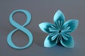 Paper flower from origami with the number eight on a gray background. March 8, International Women`s Day. Royalty Free Stock Photo