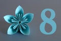 Paper flower from origami with the number eight on a gray background. March 8, International Women's Day. Royalty Free Stock Photo