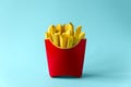 Paper French fries in red carton box on blue background. Copy space. Creative or art food concept