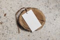 Paper gift tag, price label with string of sisal trope on round wooden board, coaster. Terazzo table background in