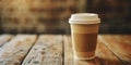 A paper glass of coffee with a lid stands on a wooden table Royalty Free Stock Photo