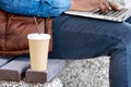 Paper glass with a drink standing on a bench next to a man sitting with a laptop Royalty Free Stock Photo