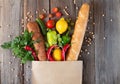 Paper grocery bag full of different food on wooden table top view with copy space Royalty Free Stock Photo