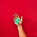 The hand of a man holds a handcraf paper skull Calaveras attributes of the Mexican holiday Calaca on a red background