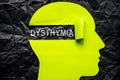 Paper head on a crumpled surface and the word dysthymia. Royalty Free Stock Photo