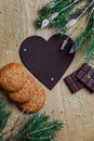 Paper heart for notes with chalk in a Christmas composition. Oatmeal cookies with milk chocolate on a natural wood board