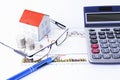 Paper home with coins and eyeglasses and pen with calculator