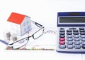 Paper house with coins and eyeglasses and calculator on chart Royalty Free Stock Photo