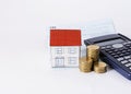 Paper house with coins stack with calculator and saving passbook