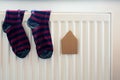 Paper house and pair of colored socks on the white radiator.