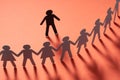 Paper human figure standing in front of paper people holding hands on red surface. Bulling, segregation, conflict Royalty Free Stock Photo