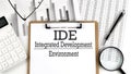 Paper with IDE INTEGRATED DEVELOPMENT ENVIRONMENT a table on charts, business concept Royalty Free Stock Photo