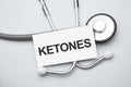 Paper with ketones on a table and grey stethoscope