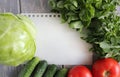 Paper leaf and composition of vegetables on grey wooden desk.