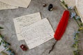 Paper letters, a pen, an inkwell and flowers lie on the table. Bright sunny day. View from above.