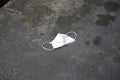 Paper Medical Face Mask used to protect against Coronavirus thrown on the ground in a parking lot. Abandoned coronavirus personal Royalty Free Stock Photo