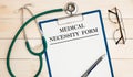 Paper with Medical necessity form on a table, stethoscope and glasses Royalty Free Stock Photo