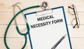 Paper with Medical necessity form on a table, stethoscope Royalty Free Stock Photo