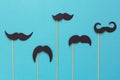 Paper mustache on booth props on blue paper background. Cut out style. Movember concept.