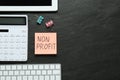 Paper note with Non Profit calculator and computer keyboard on black table, flat lay. Space for text Royalty Free Stock Photo