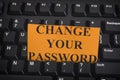 Paper note with phrase Change Your Password on black computer keyboard