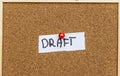 A paper note pinned to a corkboard displays the word DRAFT, indicating an initial version of a document or project. Comm Royalty Free Stock Photo