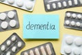 Paper note with word Dementia and pills on beige background, flat lay Royalty Free Stock Photo