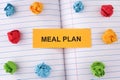 A paper note with the words Meal Plan on notebook sheet with some colorful crumpled paper balls around it